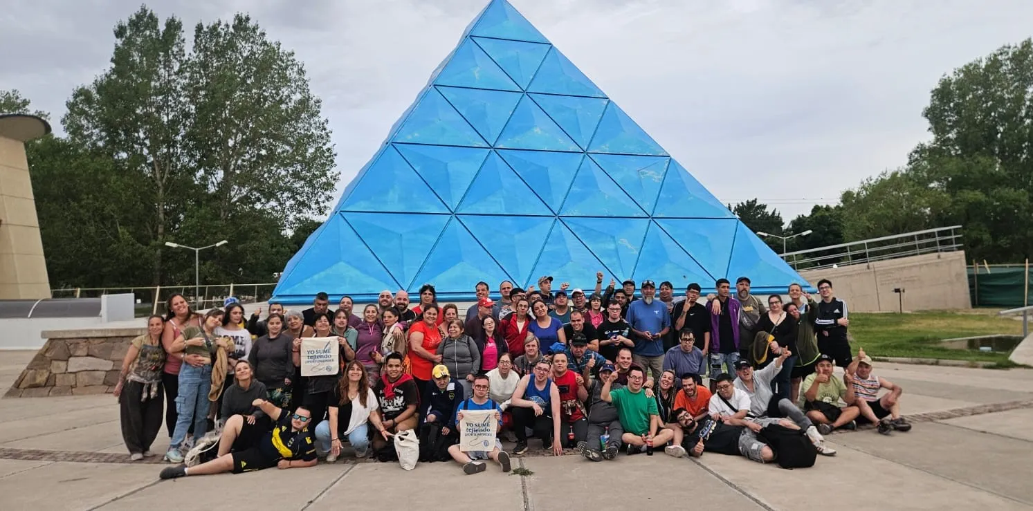 Equipo de La Rañatela reunido frente a una escultura piramidal en Mendoza